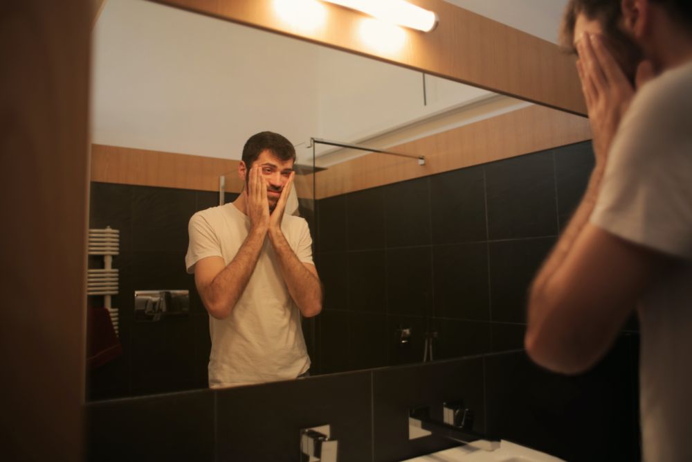tired man looking in mirror in bathroom