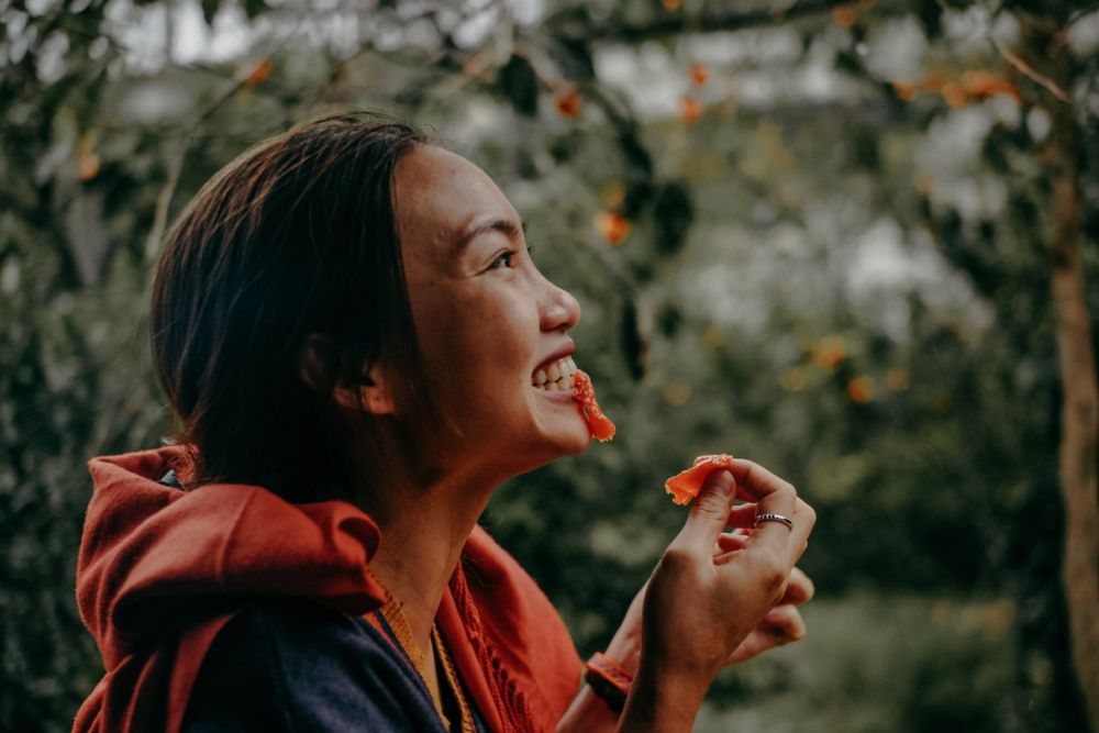 woman biting red fruit